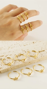 Set of 6 adjustable gold-plated rings featuring heart, plane, and crown designs on a stone surface