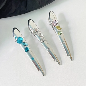 Three irregular liquid metal bow hair clips with colorful gemstones on white background