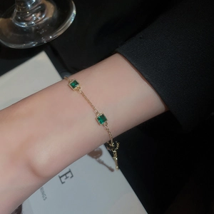Détail du bracelet en zircone vert émeraude plaqué or porté au poignet d'un mannequin