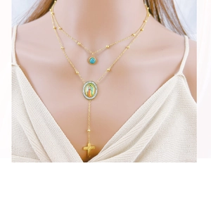 Close-up of double layer gold necklace featuring turquoise beads and Virgin Mary pendant