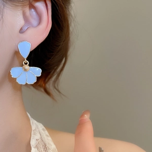 Close-up of light blue petal earrings with gold stamen on a model's ear