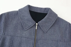 Detail der Fischgräten-Stoffstruktur auf blauer Jacke mit Metallreißverschluss
