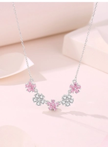 Macro detail of the silver necklace featuring five pink and white zirconia cherry blossoms