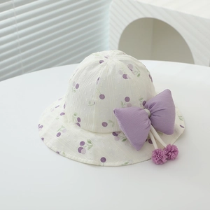 Detail of baby sun hat with fruit print, large purple bow and decorative tassel ball