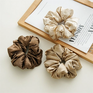 Three premium silk satin scrunchies in champagne gold and bronze on a neutral background