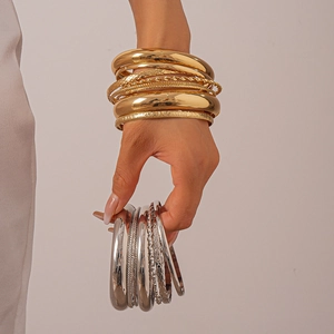 Detail of 8-piece textured gold and silver metal bangles set on model wrist