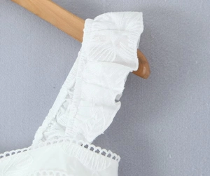Détail macro du tissu brodé blanc avec bretelles à volants et motifs de broderie anglaise