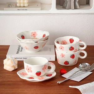 Close-up of ceramic coffee cup and saucer set with hand-painted strawberry and flowers