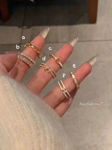 Macro shot of 6-piece gold ring set featuring bow, pearls, and H-logo on a model's hand