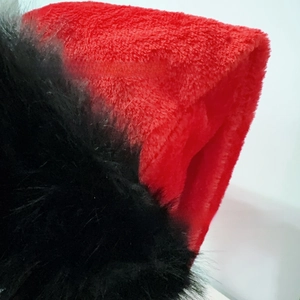 Macro view of plush red fabric with black faux fur detail on a festive Christmas hat