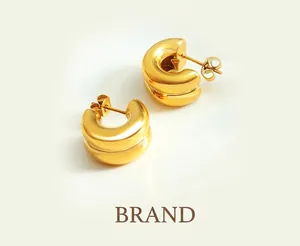 Détail de boucles d'oreilles C dorées à double couche avec finition miroir polie