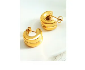 Detail of minimalist double-layered C-shaped gold earrings with polished mirror finish
