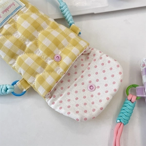 Close-up of heart-quilted yellow gingham camera bag with soft pink polka dot lining