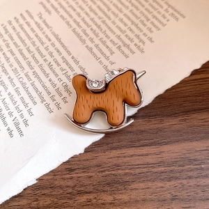 Detailed close-up of a vintage rocking horse brooch with brown texture and crystals