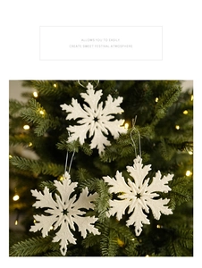 Close-up of sparkling white snowflake ornaments with silver strings on a Christmas tree