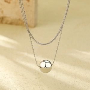 Detailed view of multilayer silver stainless steel chain with a polished ball pendant