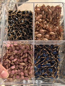 Storage box containing assorted teardrop gemstone pendants with gold plating details