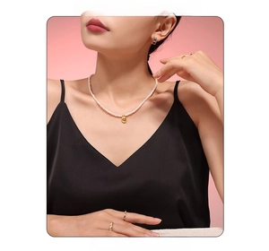 Gros plan d'un collier de perles d'eau douce vintage et pendentifs dorés sur un mannequin