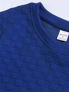 Detail of royal blue crew neck with premium checkered knit texture and wash label