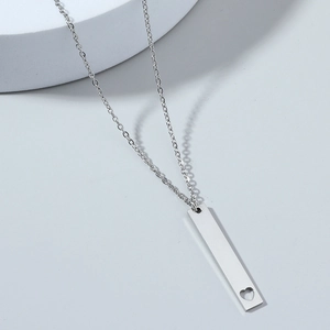 Silver stainless steel bar necklace with hollow heart pendant on geometric display