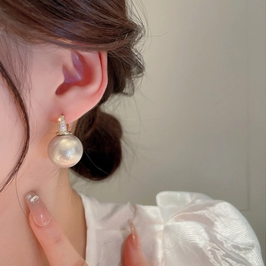Détail de grande boucle d'oreille perle avec fermoir en cristal doré sur mannequin