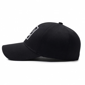 Minimalist black street style baseball cap with white graphic patch and curved brim