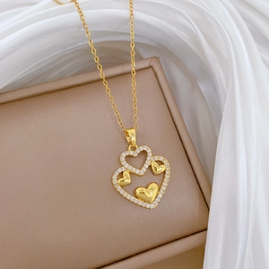 Macro shot of gold double heart pendant with sparkling crystals on jewelry box
