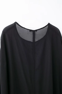 Détail du tissu en mousseline noire transparente avec couture centrale et col rond