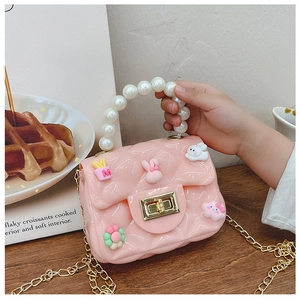Close-up of girls' pink quilted silicone bag with pearl handle and cute 3D charms
