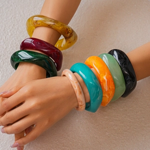 Close-up of model wearing thick resin bangles with marble texture in multiple colors