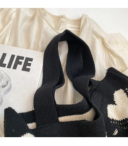 Detail of black knitted tote bag handle stitching with heart pattern on soft fabric