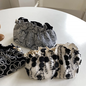 Detailed shot of embroidered clutches featuring floral patterns and pearl zipper pulls