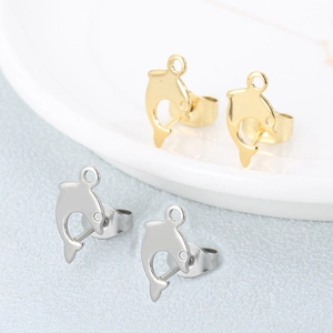 Minimalistische Delfin-Ohrstecker in Gold und Silber auf einem schicken Teller