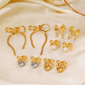 Lot de boucles d'oreilles nœuds dorés avec perles et cœurs sur soie champagne