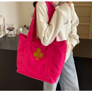 Close-up of rose red canvas tote bag with yellow club patch and frayed edge detail