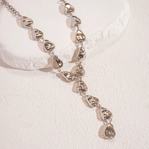 Macro view of silver Y-shaped necklace with irregular lava-textured metal charms