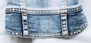 Detail of double-stitched hem and faded wash effect on a pet denim vest harness