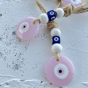 Close-up of pink evil eye star ornament with natural hemp rope and blue beads