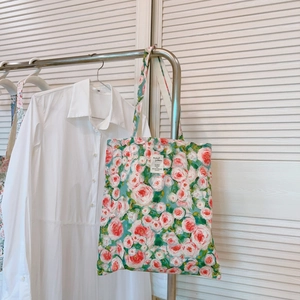Close-up of floral cotton canvas tote bag with red rose prints hanging on a rack