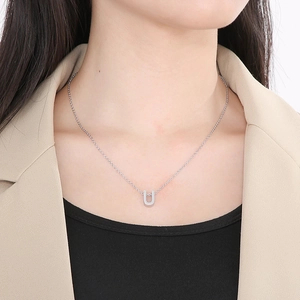 Close-up of silver U-shaped pendant necklace worn by a model in casual office attire