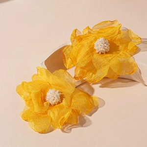 Detail view of yellow handmade lace flower earrings with soft petals and pearl centers