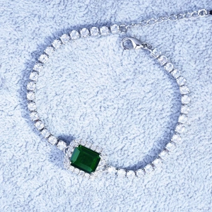 Detailed view of emerald cut green gemstone bracelet with pavé setting on plush fabric