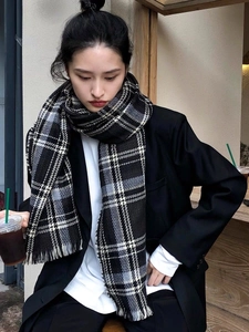 Écharpe classique à carreaux noir et blanc avec franges portée par un mannequin en extérieur