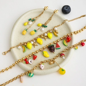 Detailed flat lay of gold fruit jewelry set with pearls and enamel pendants