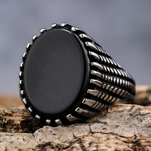 Vintage stainless steel ring with black oval gemstone and textured sides on bark