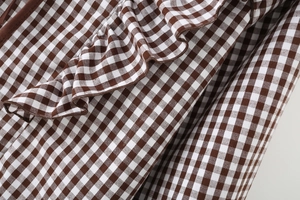 Detail of brown and white gingham fabric featuring ruffle edges and brown piping trim