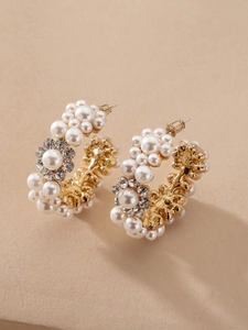 Detail of C-shaped gold earring with pearls and rhinestone flower in macro view