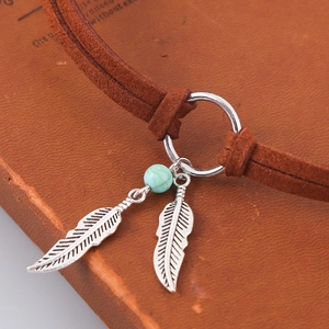 Detail of bohemian necklace with turquoise bead, silver feathers and dark brown leather cord