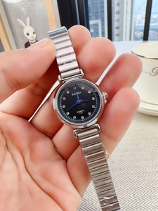 Close-up of black dial quartz watch with crystal indices and silver metal strap