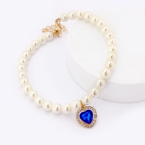 Close-up of pearl pet necklace with blue heart gemstone pendant and gold chain